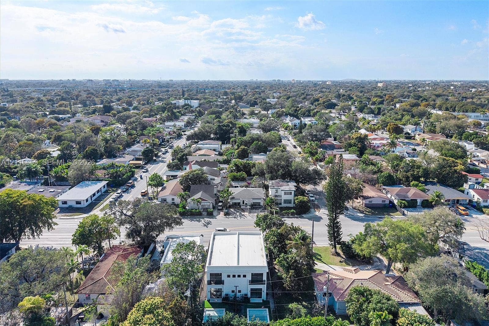 4719 N Miami Avenue, Miami, FL 33127 Aerial perspective of a multi-story residence featuring a flat roofline, two levels of balcony structures, a ground-level rectangular swimming pool, and established surrounding canopy trees
