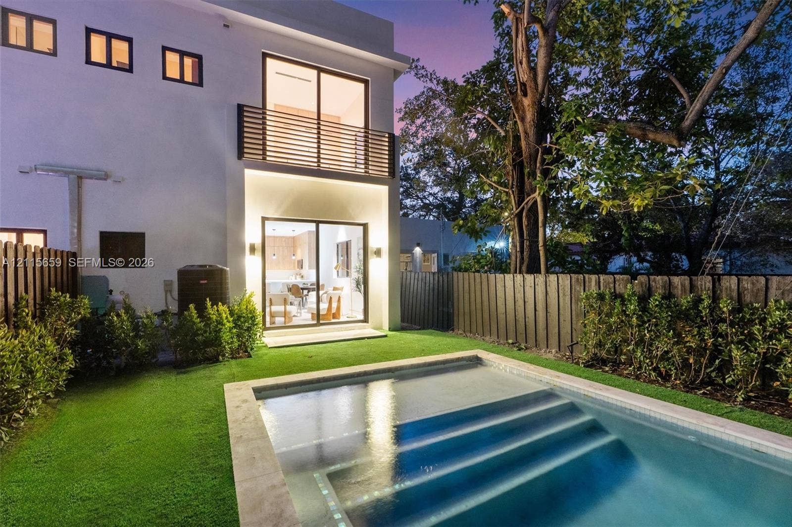 4719 N Miami Avenue, Miami, FL 33127 Modern exterior featuring a swimming pool with integrated stairs, synthetic lawn, wood-slat upper balcony railing, and floor-to-ceiling sliding glass doors
