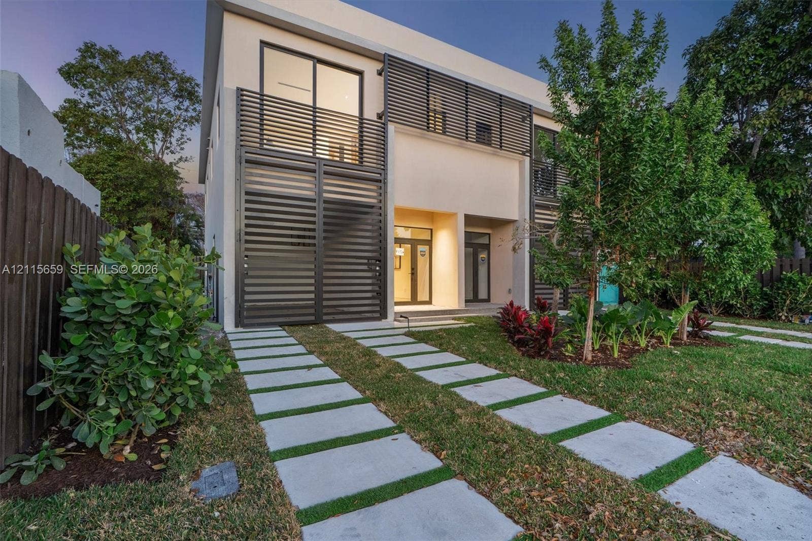 4719 N Miami Avenue, Miami, FL 33127 Modern two-story residence featuring a smooth stucco exterior, horizontal metal privacy screening, integrated balcony, and a permeable paver driveway system
