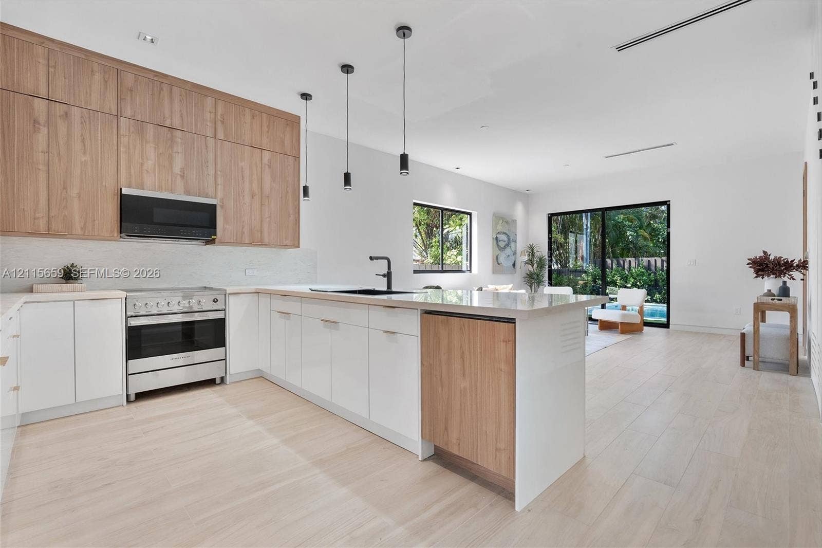 4719 N Miami Avenue, Miami, FL 33127 Kitchen featuring two-tone wood-finish and matte white cabinetry, stone-surfaced island, stainless steel range with overhead microwave, and wood-finish flooring