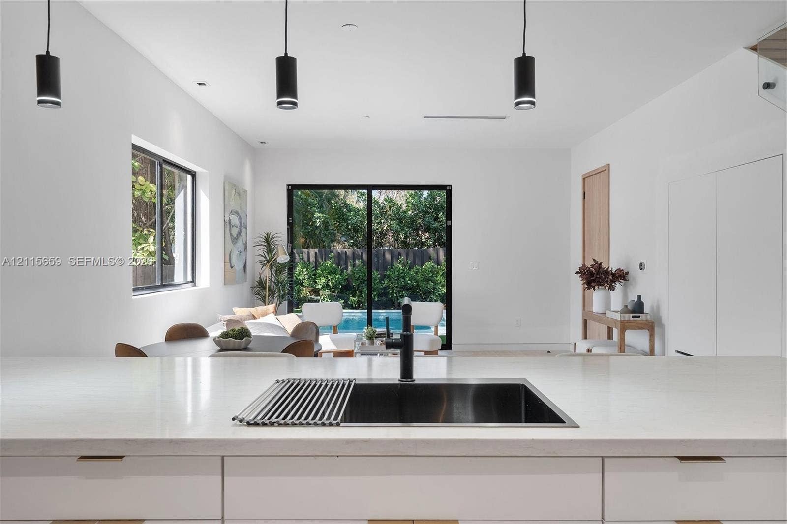 4719 N Miami Avenue, Miami, FL 33127 Kitchen featuring a stone-surface island, undermount stainless steel sink, matte black faucet, and three modern pendant lights