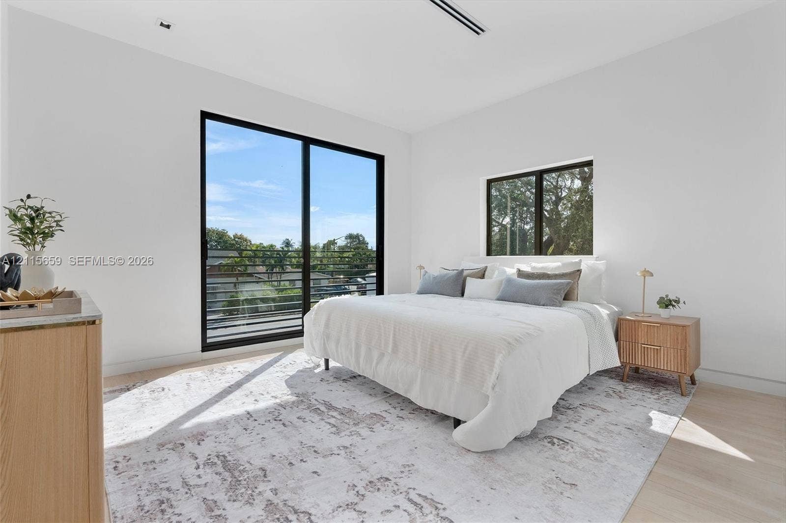 4719 N Miami Avenue, Miami, FL 33127 Floor-to-ceiling black-framed sliding glass door with a balcony railing, neutral-toned walls, wood-finish flooring, and recessed ceiling lighting