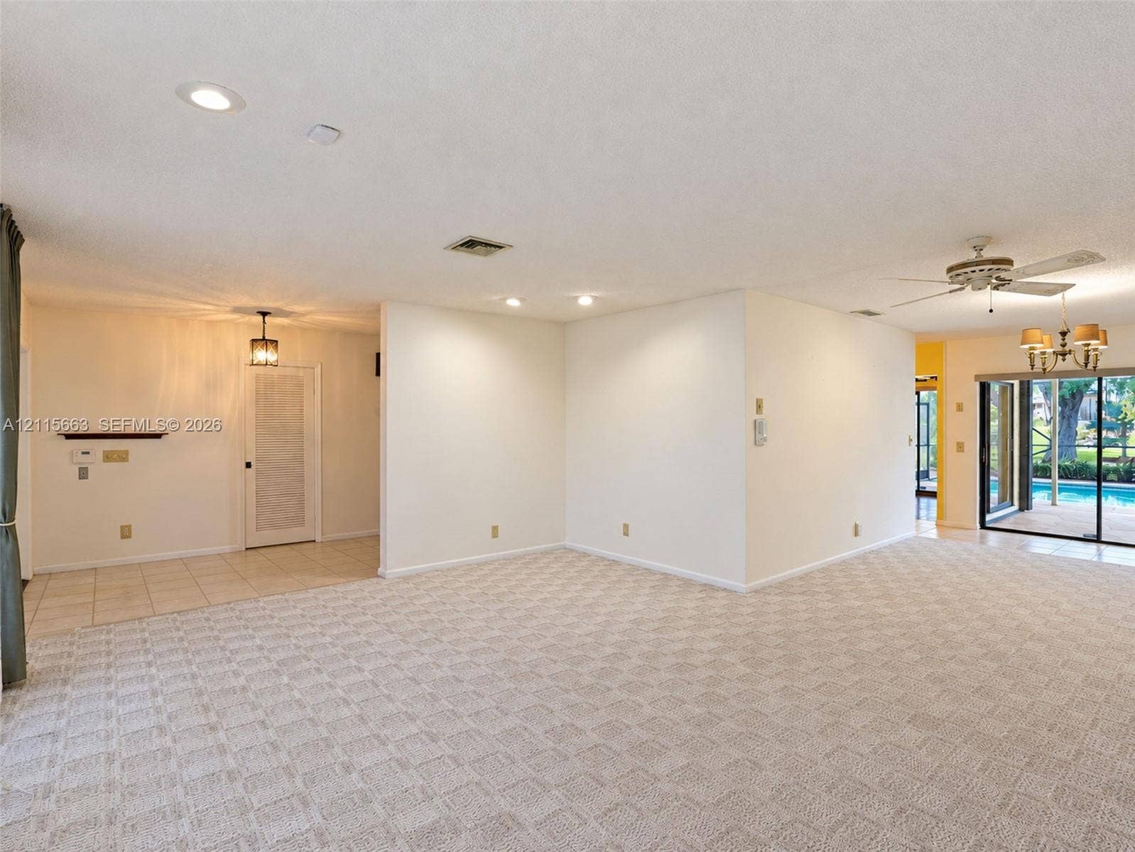 9788 NW 18th Street, Coral Springs, FL 33071 Neutral-toned carpeting, recessed lighting, multi-arm chandelier, ceiling fan, and sliding glass doors