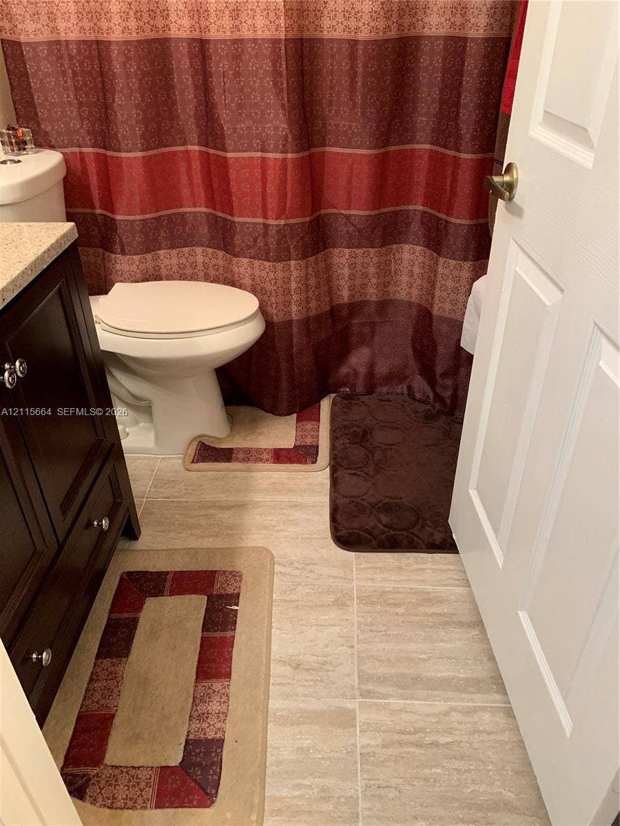 19409 NW 24th Place, Pembroke Pines, FL 33029 Dark-finish cabinetry featuring a light-toned solid surface countertop, ceramic tile flooring, and a standard-height toilet