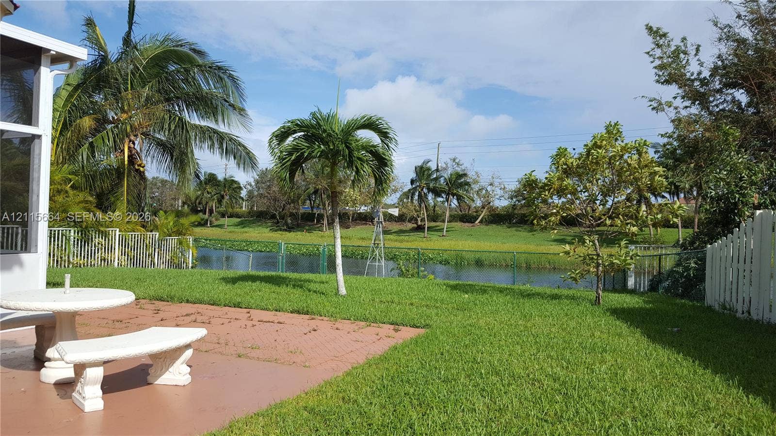 19409 NW 24th Place, Pembroke Pines, FL 33029 Backyard featuring a paved patio, manicured lawn, established palm trees, and direct waterfront access