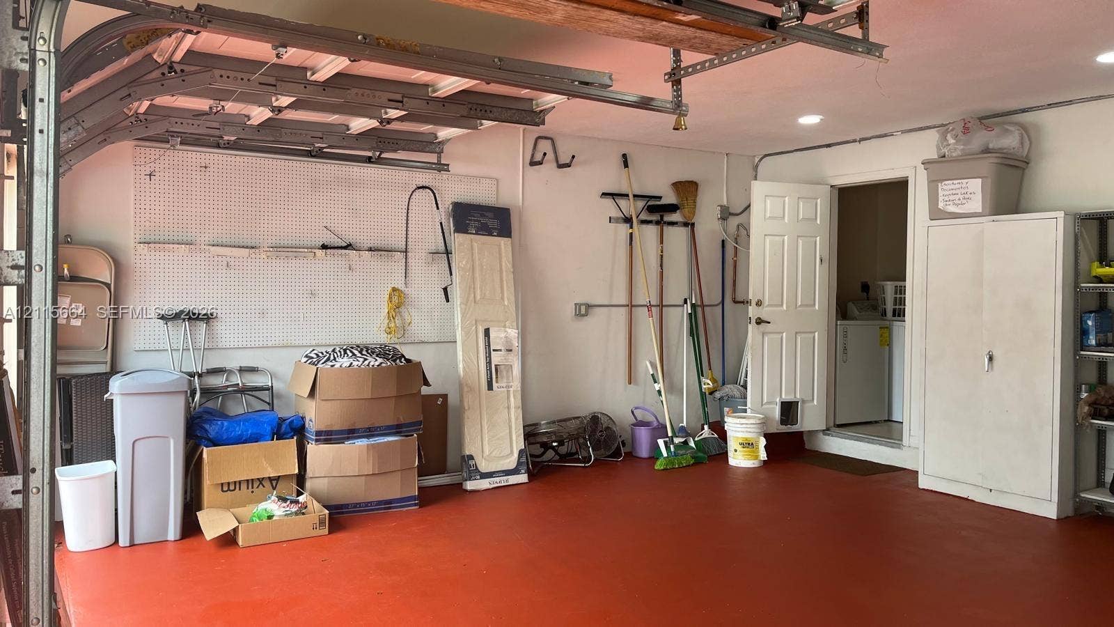19409 NW 24th Place, Pembroke Pines, FL 33029 Attached garage featuring recessed lighting, a painted floor surface, mounted pegboard wall organizers, and a metal storage cabinet