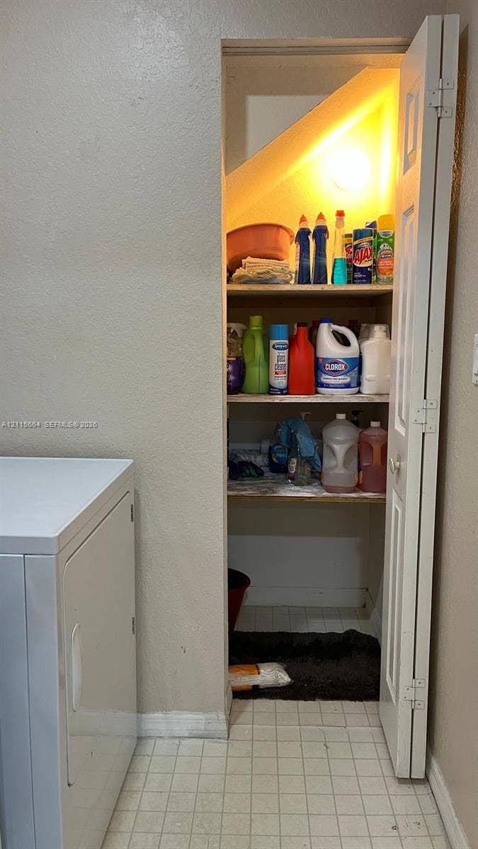 19409 NW 24th Place, Pembroke Pines, FL 33029 Storage closet featuring three levels of built-in shelving, white bi-fold door, and light fixture