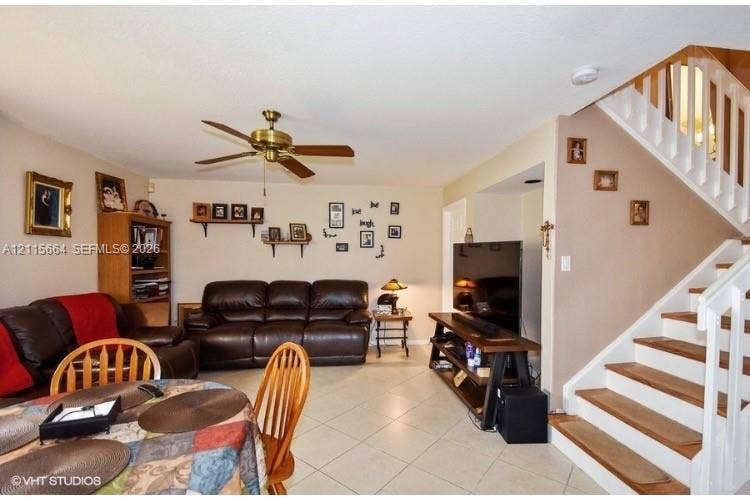 19409 NW 24th Place, Pembroke Pines, FL 33029 Open-concept floor plan featuring neutral tile flooring, a multi-blade ceiling fan, and a staircase with white balusters and wood-finished treads