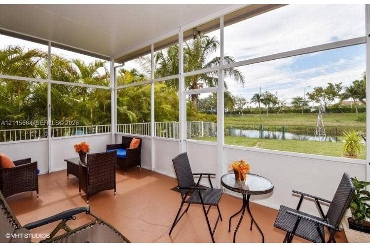 19409 NW 24th Place, Pembroke Pines, FL 33029 Screened-in lanai featuring a solid roof, concrete flooring, and metal frame enclosure overlooking a grassed exterior space with water frontage and mature landscaping