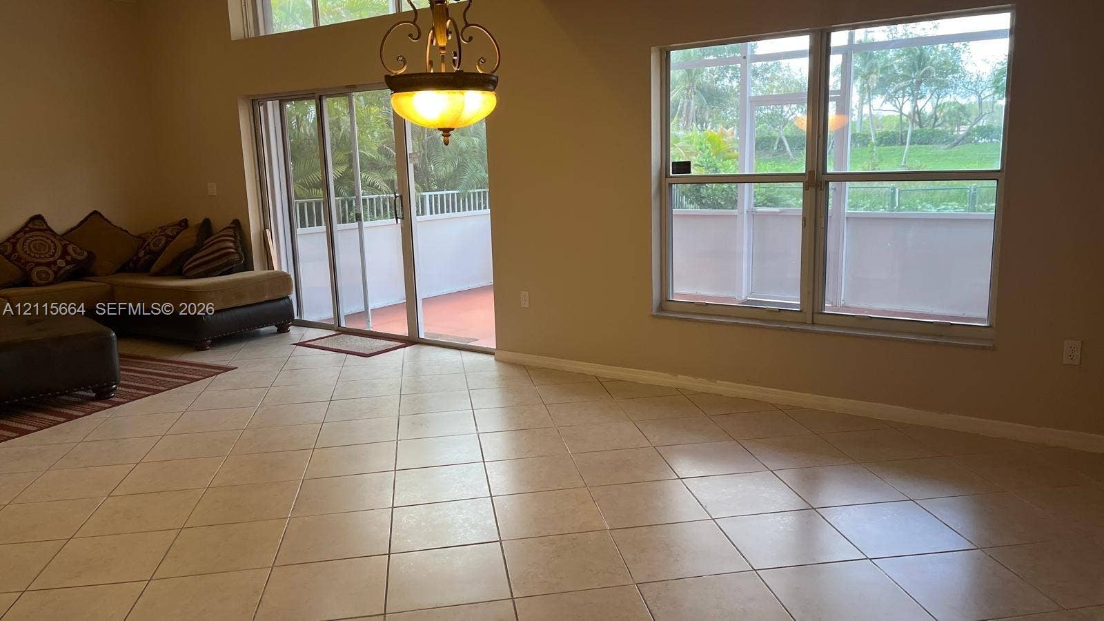 19409 NW 24th Place, Pembroke Pines, FL 33029 Large-format neutral tile flooring, vaulted ceilings, dual-pane windows, and a sliding glass door providing access to a screened-in lanai