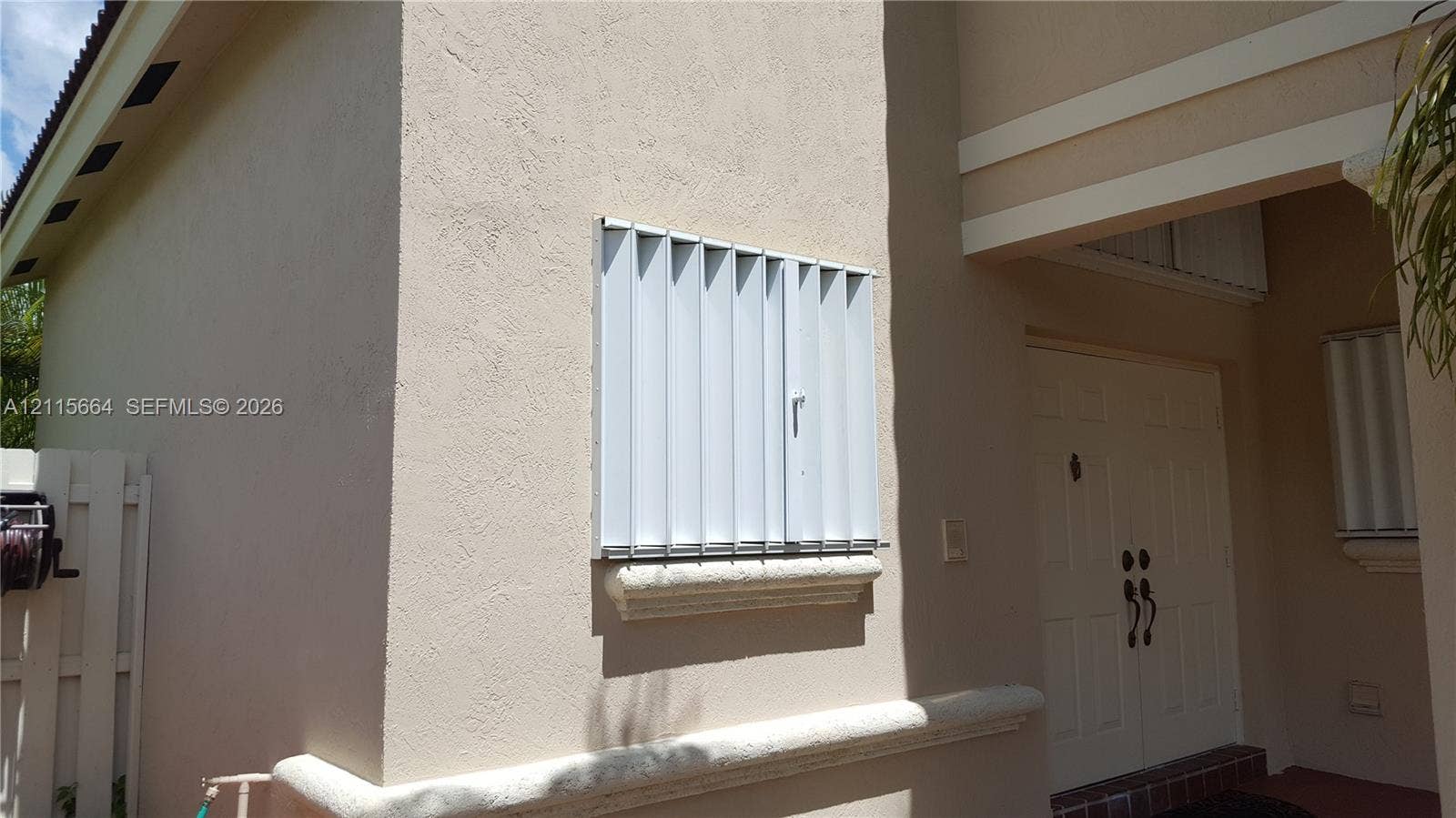 19409 NW 24th Place, Pembroke Pines, FL 33029 Stucco exterior featuring dual entry doors, metallic storm shutters, and decorative horizontal masonry trim