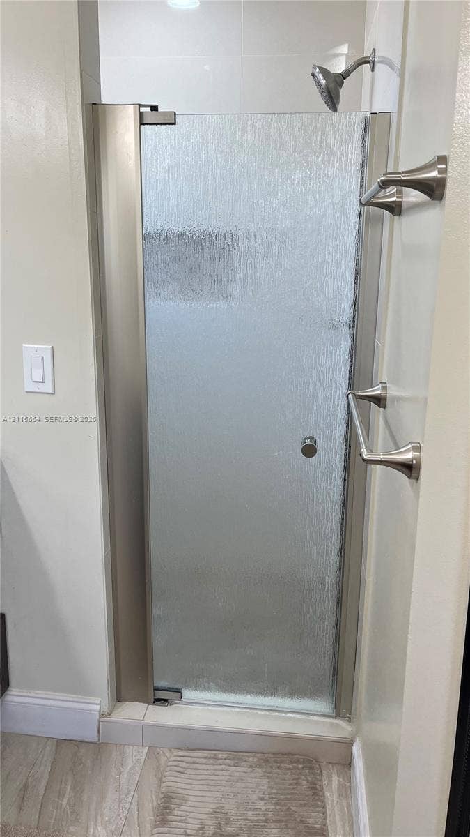 19409 NW 24th Place, Pembroke Pines, FL 33029 Shower enclosure featuring textured glass, a metal-finish frame, a wall-mounted shower head, and dual metal-finish wall-mounted towel bars