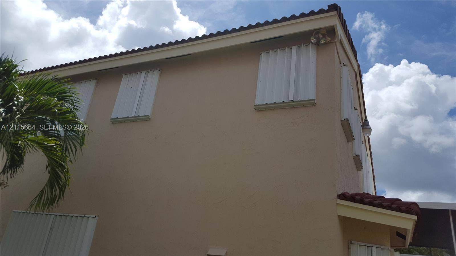 19409 NW 24th Place, Pembroke Pines, FL 33029 Exterior wall featuring smooth stucco finish, barrel tile roofline, and installed metal storm shutters