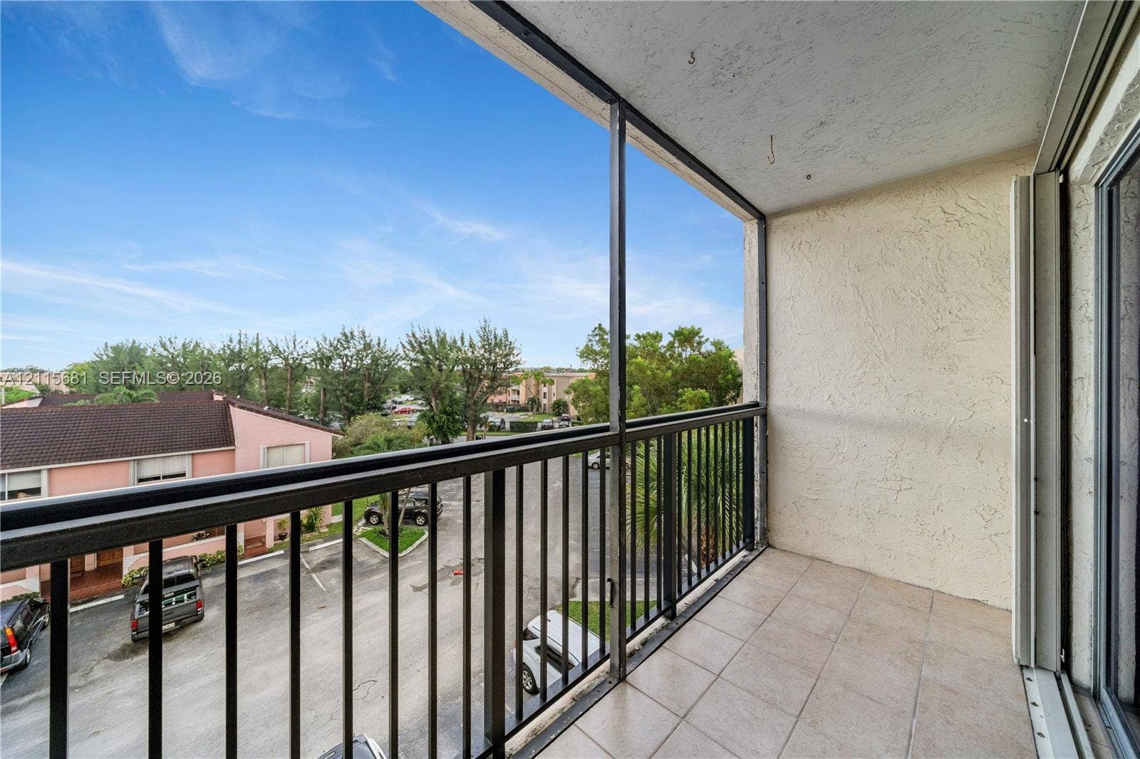 Covered balcony featuring a screen enclosure, metal railings, and tile flooring