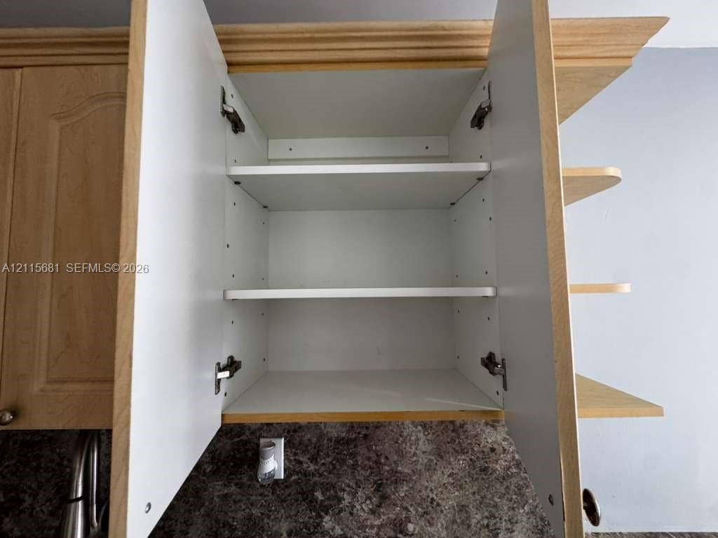 Wall-mounted cabinetry featuring wood-finish panel doors, adjustable interior shelving, and external open shelving elements