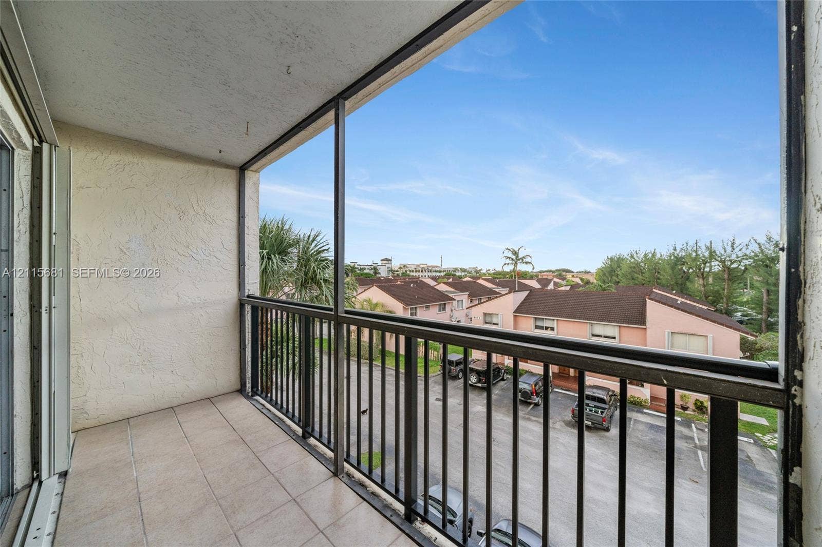Screened-in balcony featuring tile flooring and a black metal railing