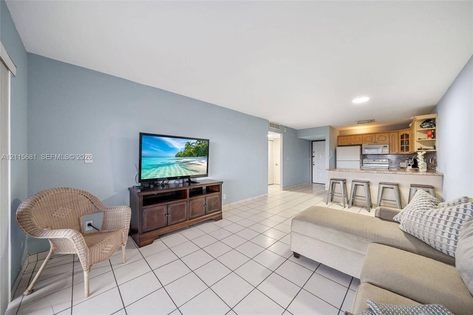 Open-concept living space featuring ceramic tile flooring, recessed lighting, and a kitchen equipped with cabinetry, a breakfast bar, and stainless steel appliances