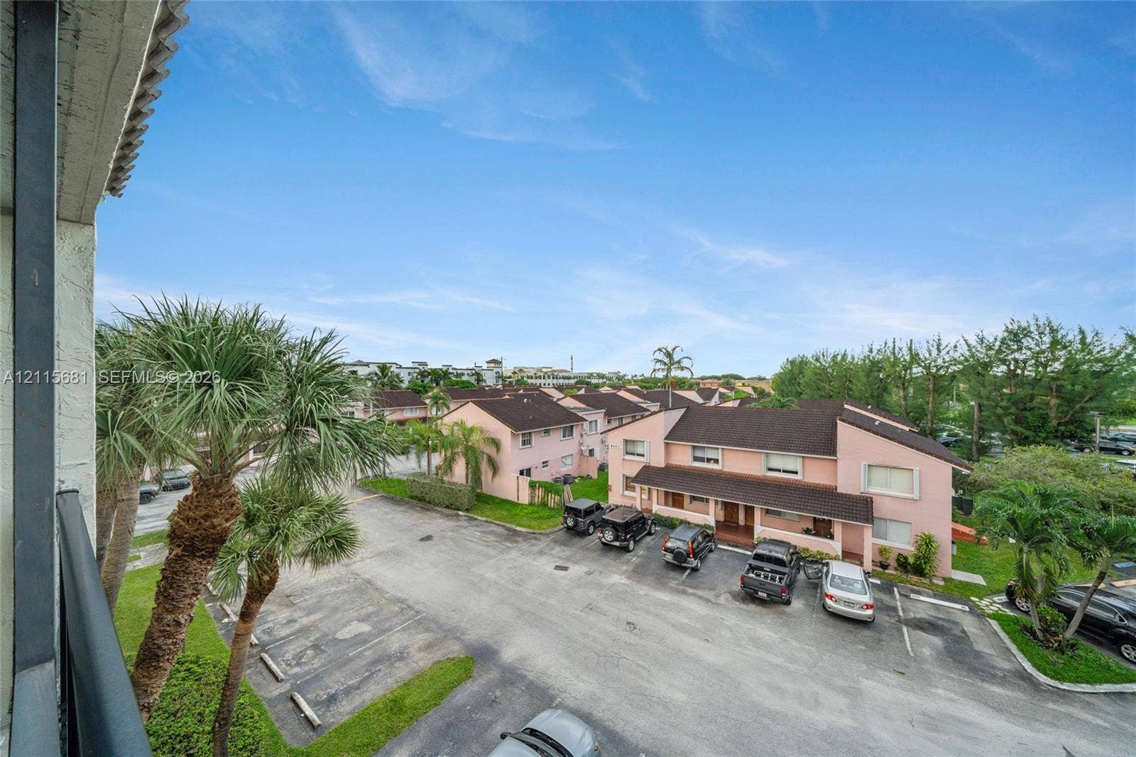 Exterior view featuring multi-story structures with stucco siding and asphalt shingle roofing, integrated parking area, and mature palm trees