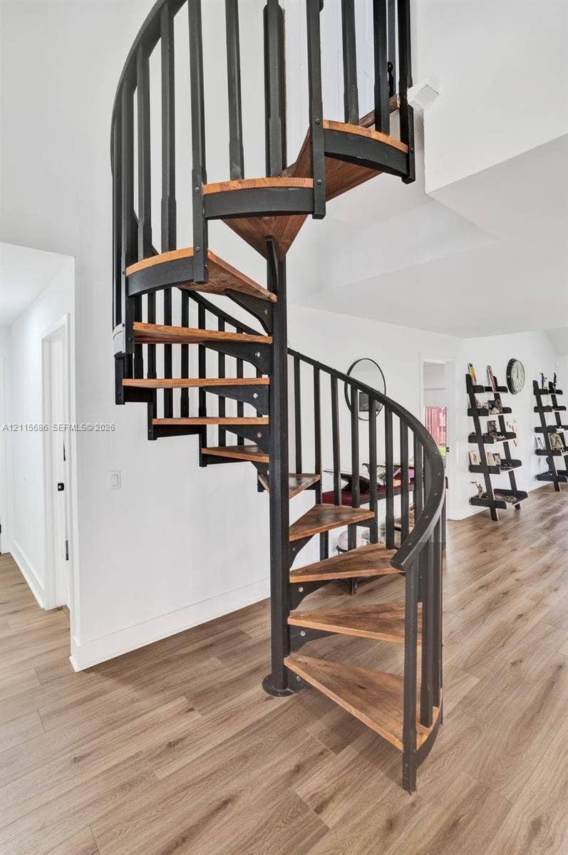 8946 SW 150th Ct Circle E, Miami, Miami, FL 33196 Spiral staircase featuring matte black metal railings and natural wood-finish treads, set against wood-finish flooring