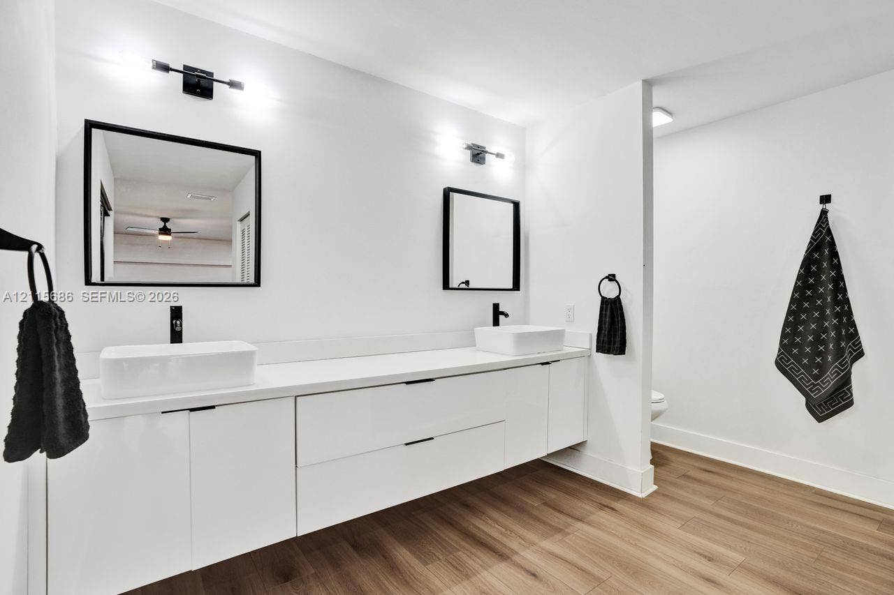 8946 SW 150th Ct Circle E, Miami, Miami, FL 33196 Floating double vanity with rectangular vessel sinks, matte black fixtures, framed mirrors, and wood-finish flooring