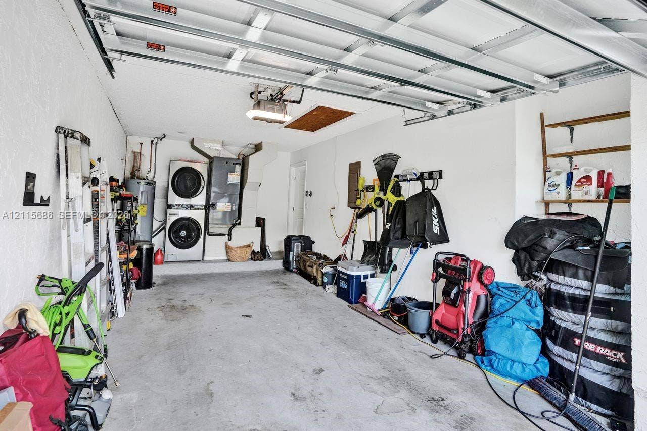 8946 SW 150th Ct Circle E, Miami, Miami, FL 33196 Garage interior featuring concrete flooring, an overhead sectional garage door mechanism, and a dedicated laundry area with stacked appliance hookups