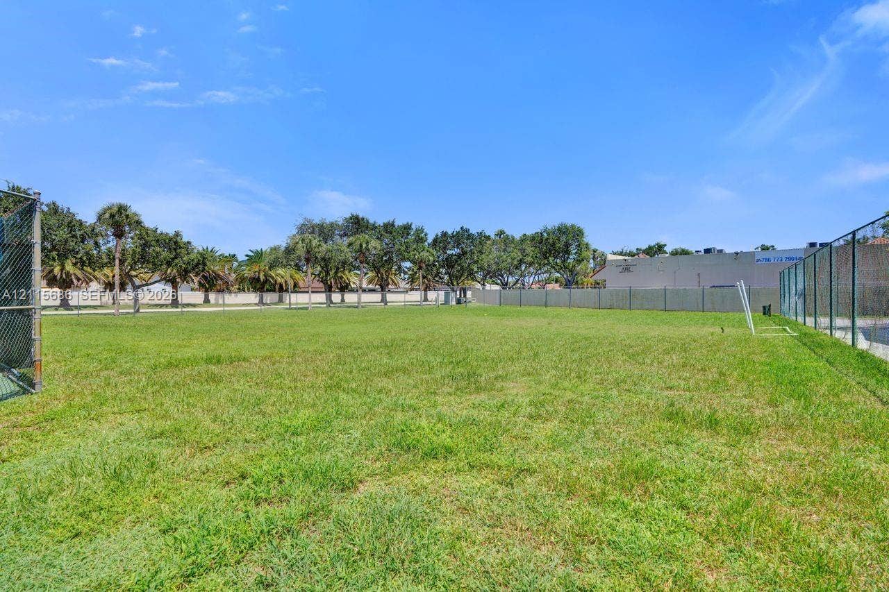 8946 SW 150th Ct Circle E, Miami, Miami, FL 33196 Expansive open-space grounds featuring perimeter chain-link fencing, mature palm trees, and level grass terrain