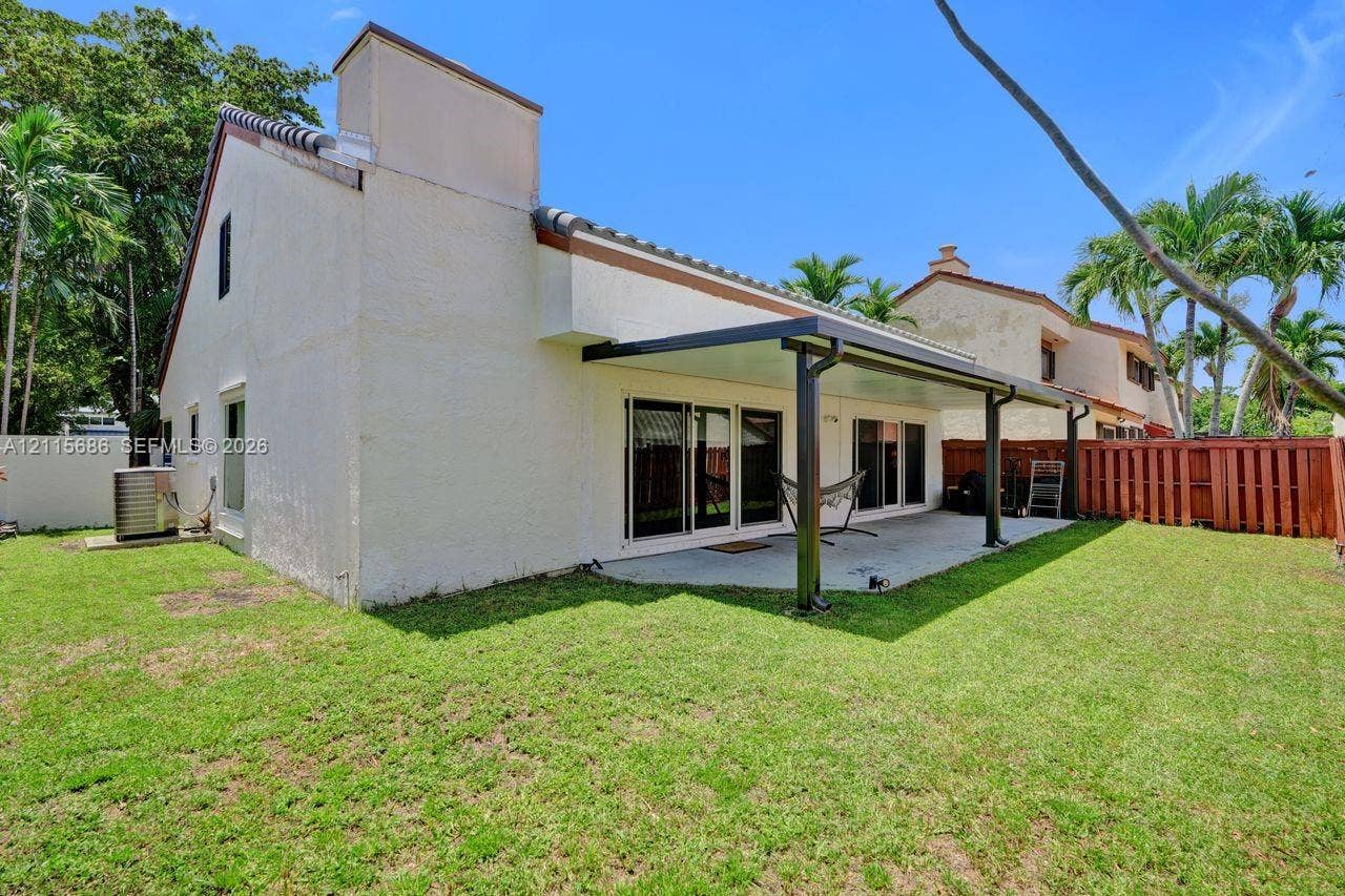 8946 SW 150th Ct Circle E, Miami, Miami, FL 33196 Rear exterior featuring a covered patio, concrete flooring, sliding glass doors, and a wood privacy fence