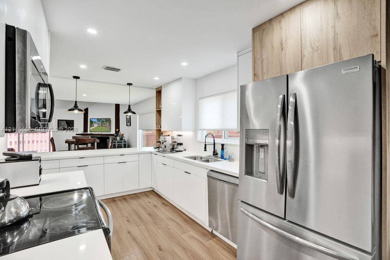 8946 SW 150th Ct Circle E, Miami, Miami, FL 33196 Kitchen featuring high-gloss white cabinetry, stainless steel appliances, wood-finish flooring, recessed lighting, and a neutral solid-surface countertop
