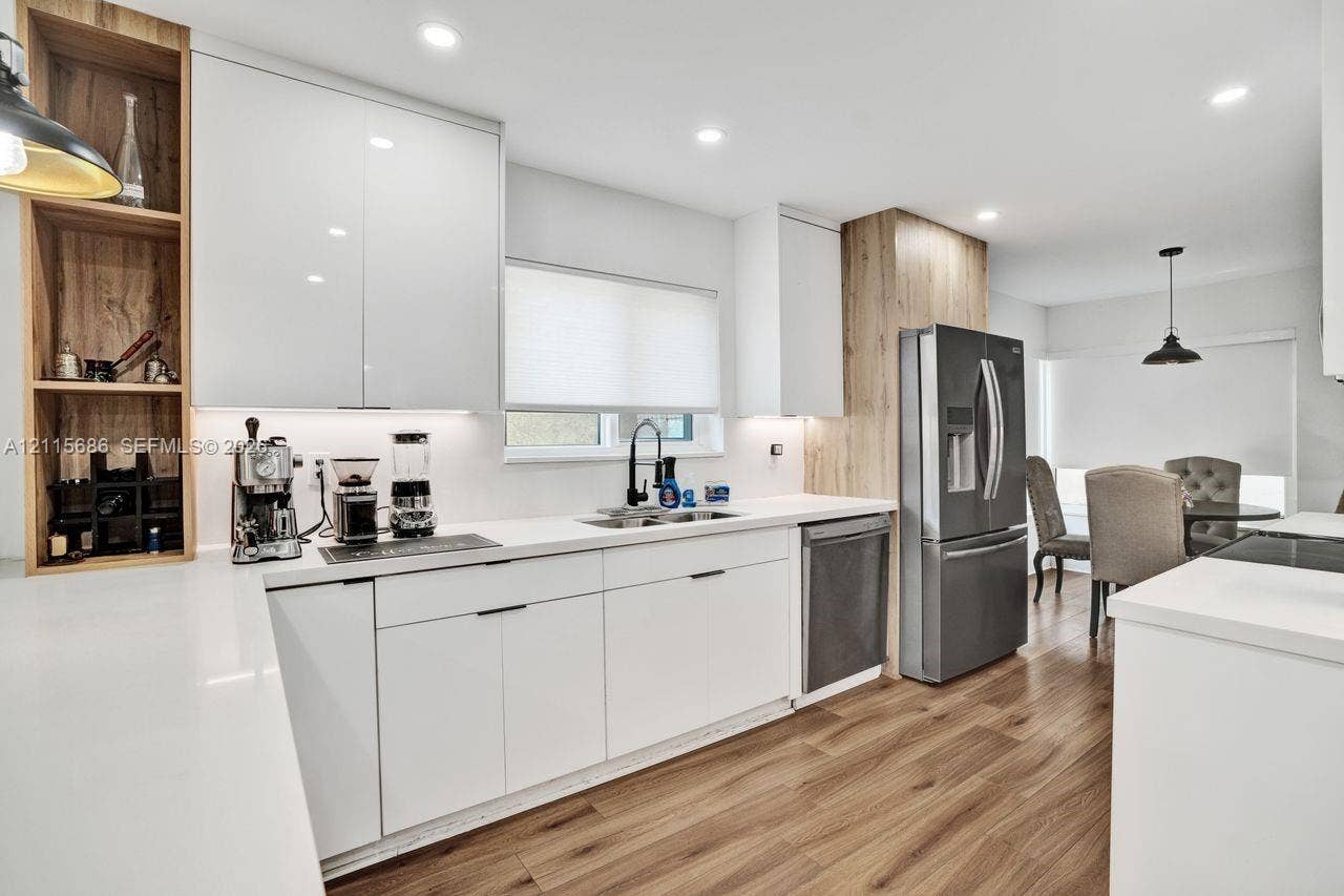 8946 SW 150th Ct Circle E, Miami, Miami, FL 33196 Kitchen featuring white flat-panel cabinetry, light-toned wood-finish vertical accents, solid-surface countertops, recessed lighting, and wood-finish flooring