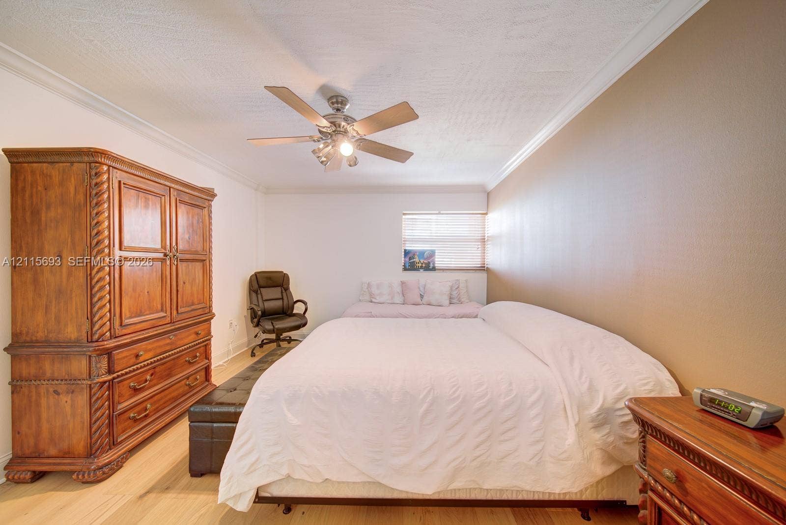 Room featuring wood-finish flooring, crown molding, and a ceiling fan with integrated lighting
