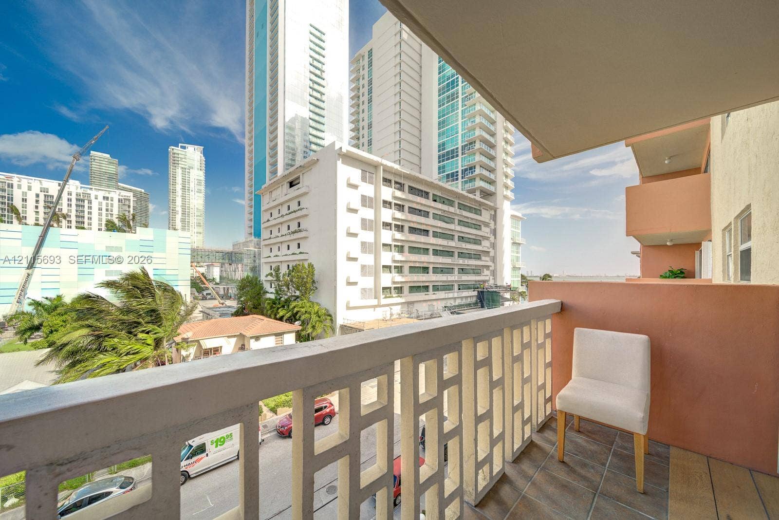 Covered balcony featuring geometric concrete railing, tile flooring, and solid wall partition