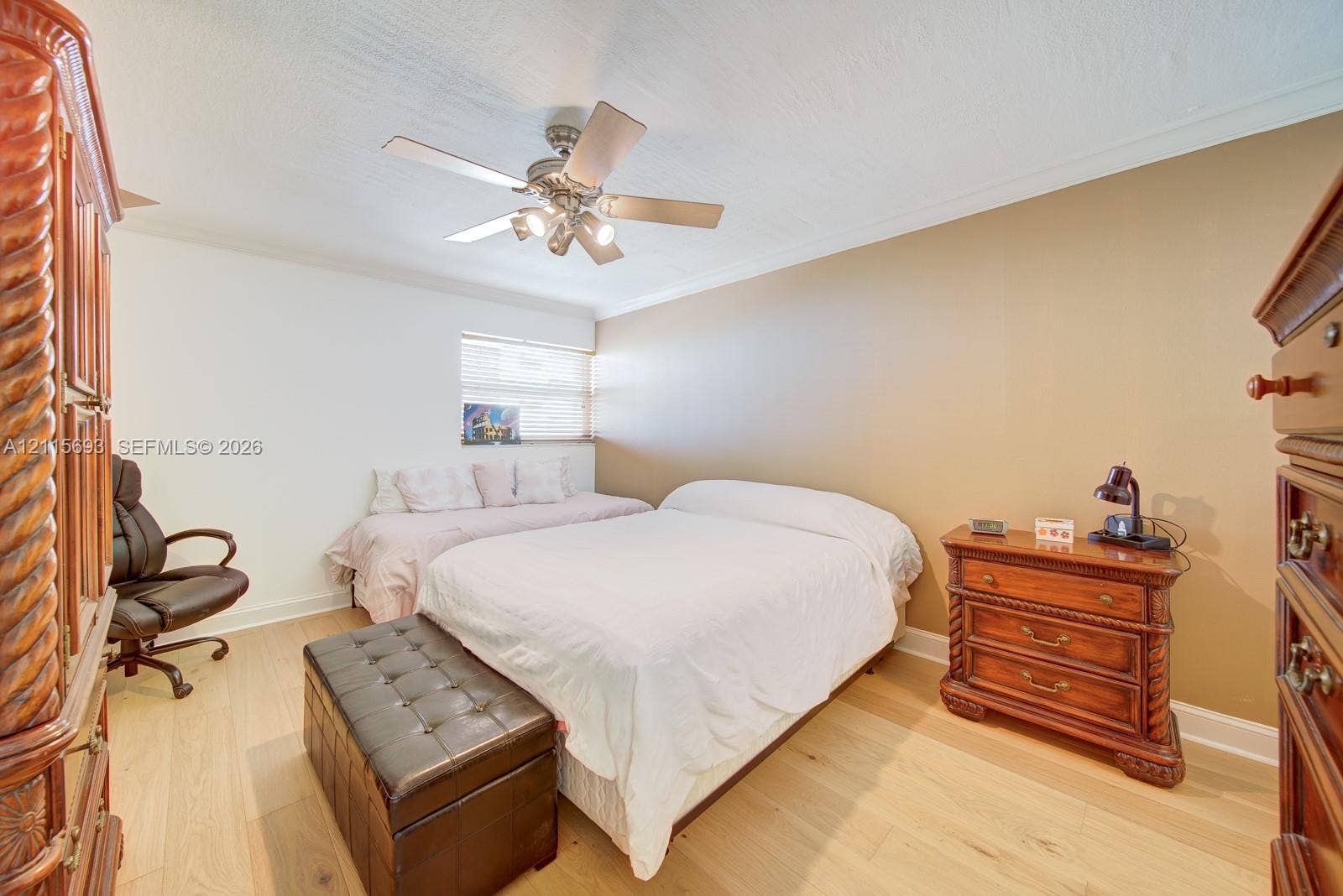 Neutral-toned room featuring wood-finish flooring, a ceiling fan with integrated lighting, and a window with blinds