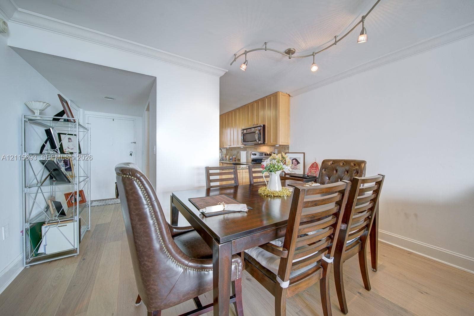 Wood-finish flooring, crown molding, and modern curved track lighting