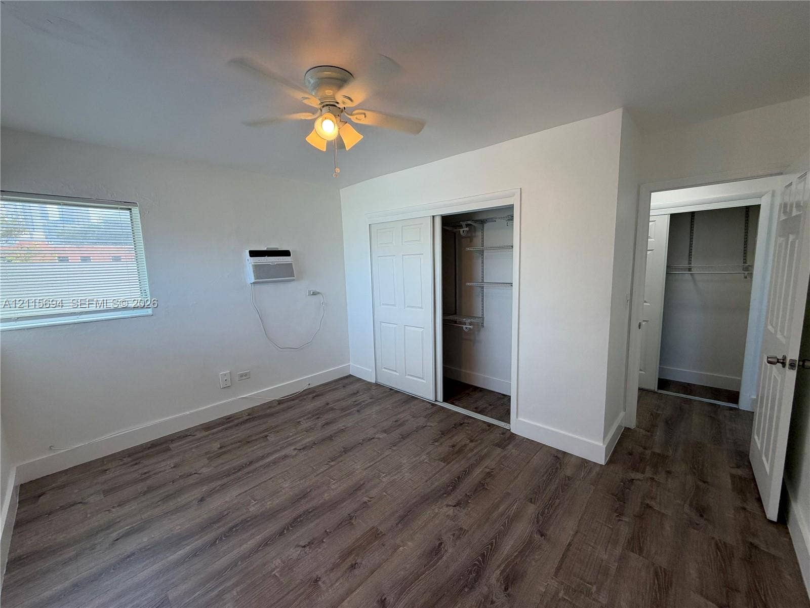 619 SW 7th Avenue, #7, Miami, Miami, FL 33130 Wood-finish flooring, ceiling fan with integrated lighting, window with horizontal blinds, built-in closet storage, and wall-mounted air conditioning unit