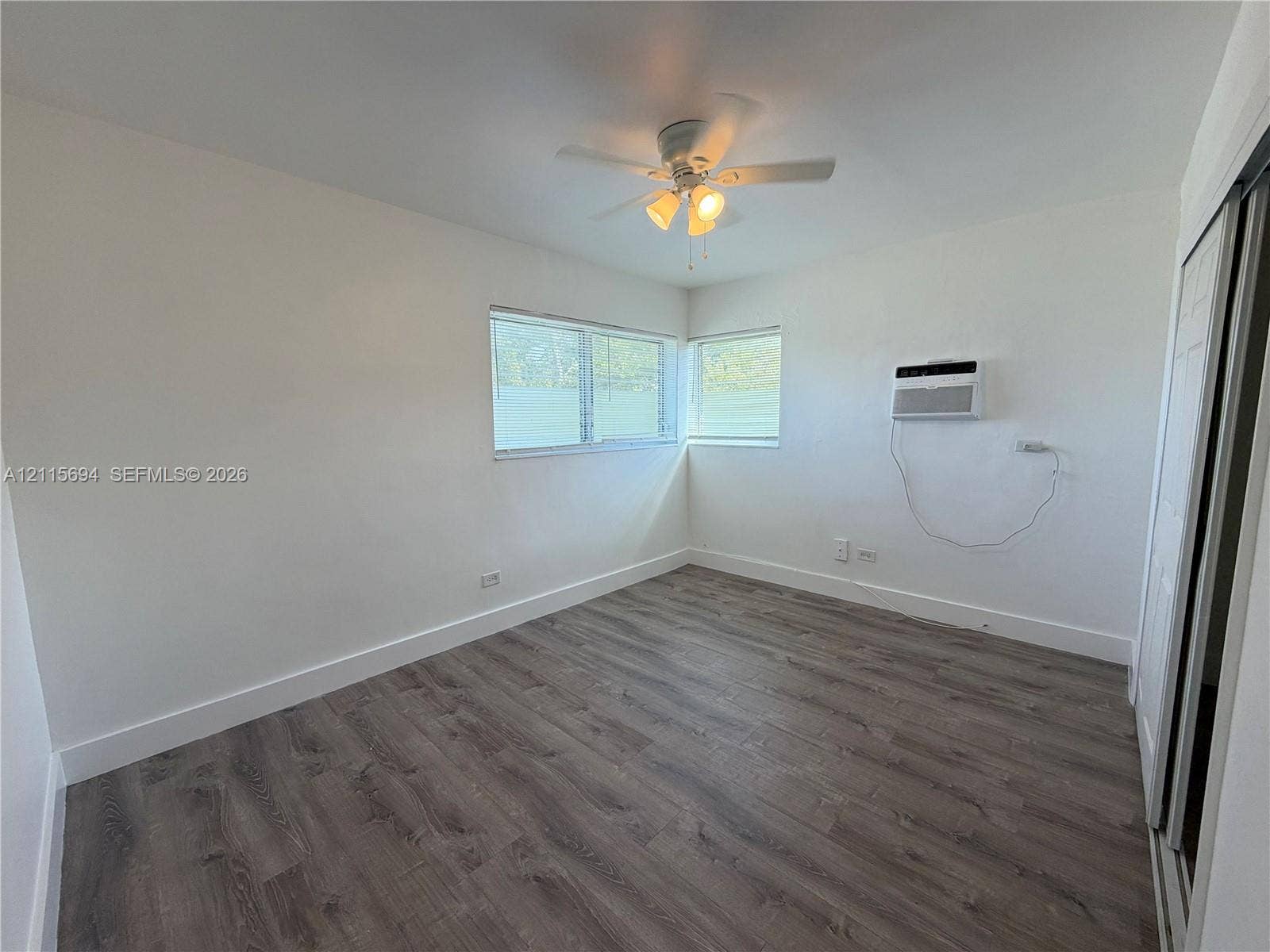 619 SW 7th Avenue, #7, Miami, Miami, FL 33130 Interior space featuring wood-finish flooring, a ceiling fan with integrated lighting, dual windows, and a wall-mounted air conditioning unit