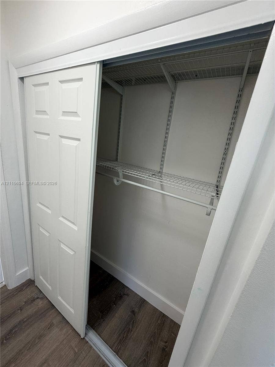 619 SW 7th Avenue, #7, Miami, Miami, FL 33130 Six-panel sliding closet door featuring wire shelving and a built-in hanging rod above wood-finish flooring