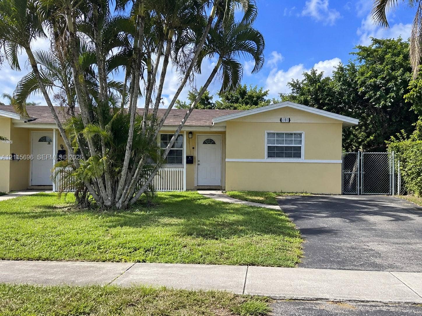 1101 NW 55th Avenue, #B, Lauderhill, Lauderhill, FL 33313 Single-story residence featuring a paved driveway, front lawn, mature palm trees, white exterior trim, and gated side access