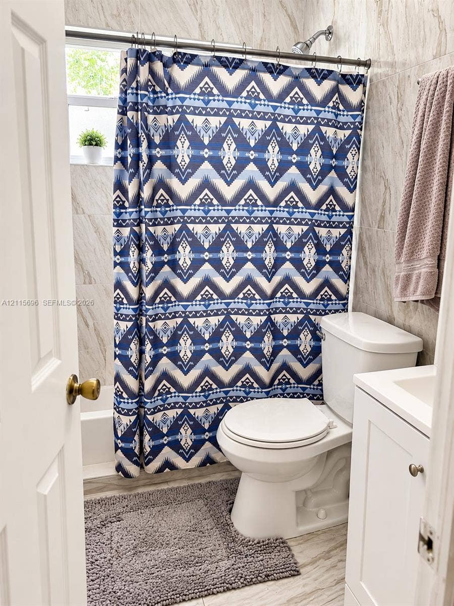 1101 NW 55th Avenue, #B, Lauderhill, Lauderhill, FL 33313 Bathroom featuring floor-to-ceiling neutral-toned tile, a white single-door vanity, a white porcelain toilet, and a combined tub and shower unit