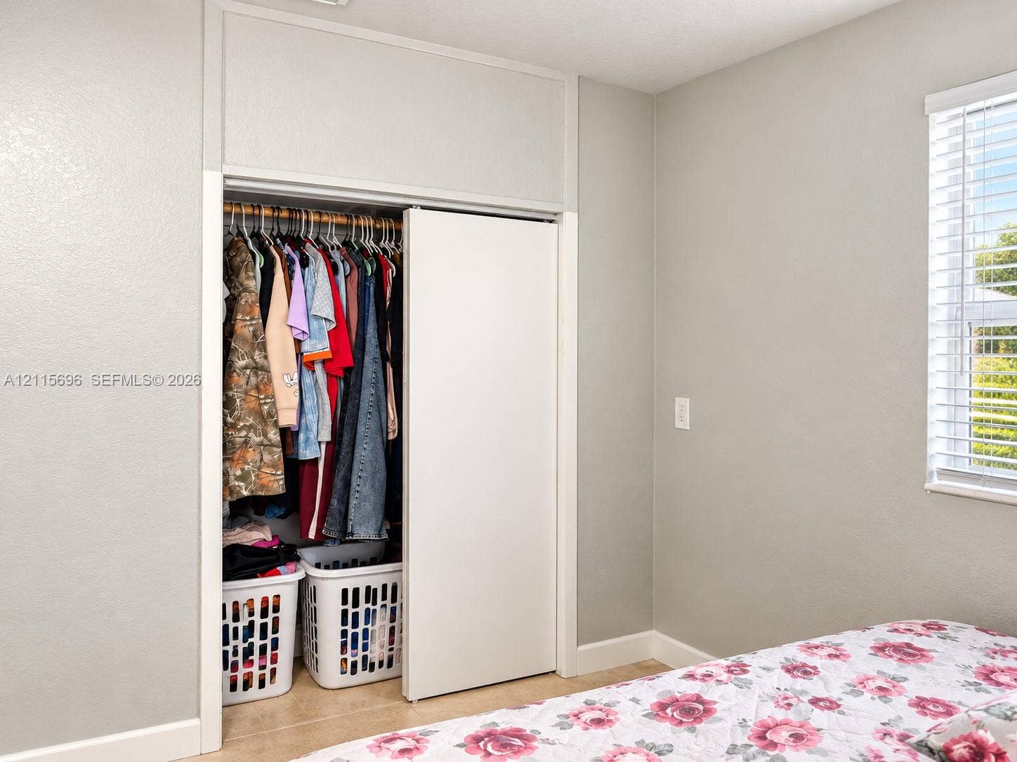 1101 NW 55th Avenue, #B, Lauderhill, Lauderhill, FL 33313 Built-in closet featuring floor-to-ceiling white sliding doors, neutral wall paint, and a horizontal window with white horizontal blinds