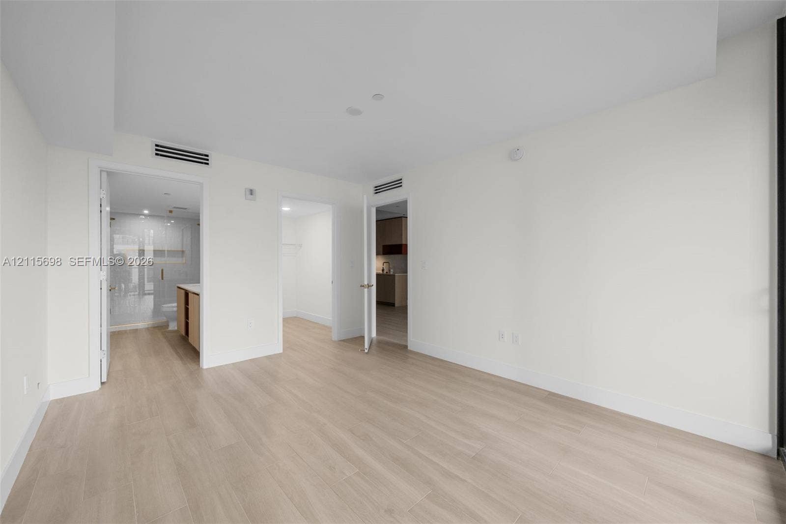 Master Bedroom with en suite bath Neutral interior space featuring wood-finish flooring, recessed ceiling lighting, and crisp white wall finishes
