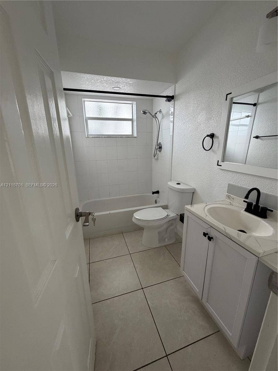 8641 NW 25th Court, #864, Sunrise, Sunrise, FL 33322 Bathroom featuring large-format floor tile, vanity with stone-surfaced countertop, integrated sink with matte black faucet, and a shower-tub combination with white tile surround