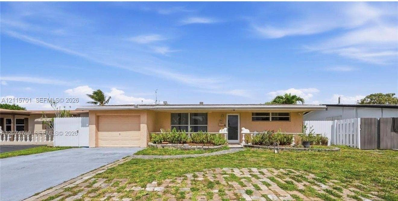 8641 NW 25th Court, #864, Sunrise, Sunrise, FL 33322 Single-story residence featuring a stucco exterior, attached garage, paved driveway, brick-accented front lawn, and privacy fencing