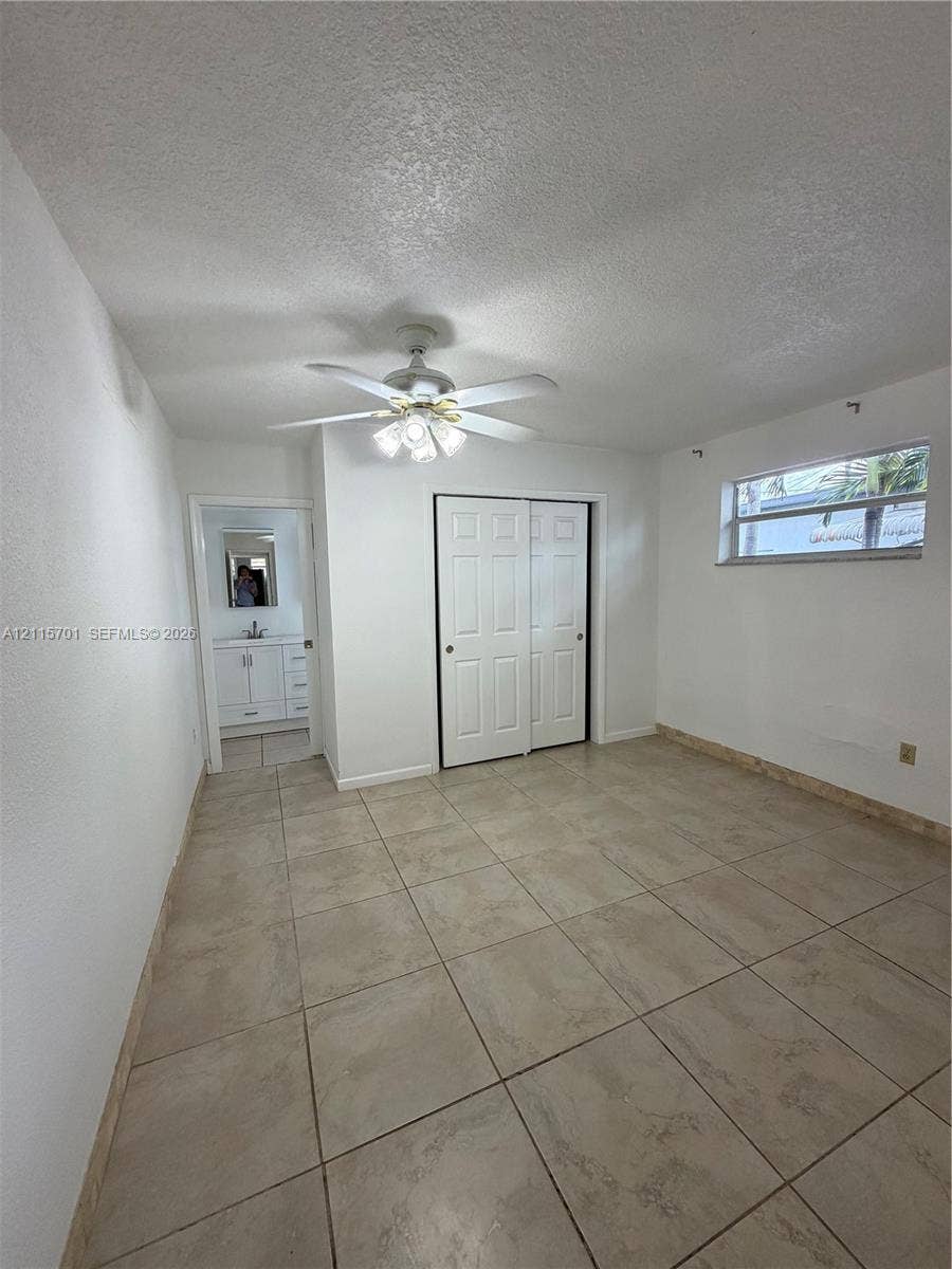 8641 NW 25th Court, #864, Sunrise, Sunrise, FL 33322 Room featuring neutral tile flooring, multi-panel bi-fold closet doors, a central ceiling fan with integrated lighting, and a single-pane horizontal window