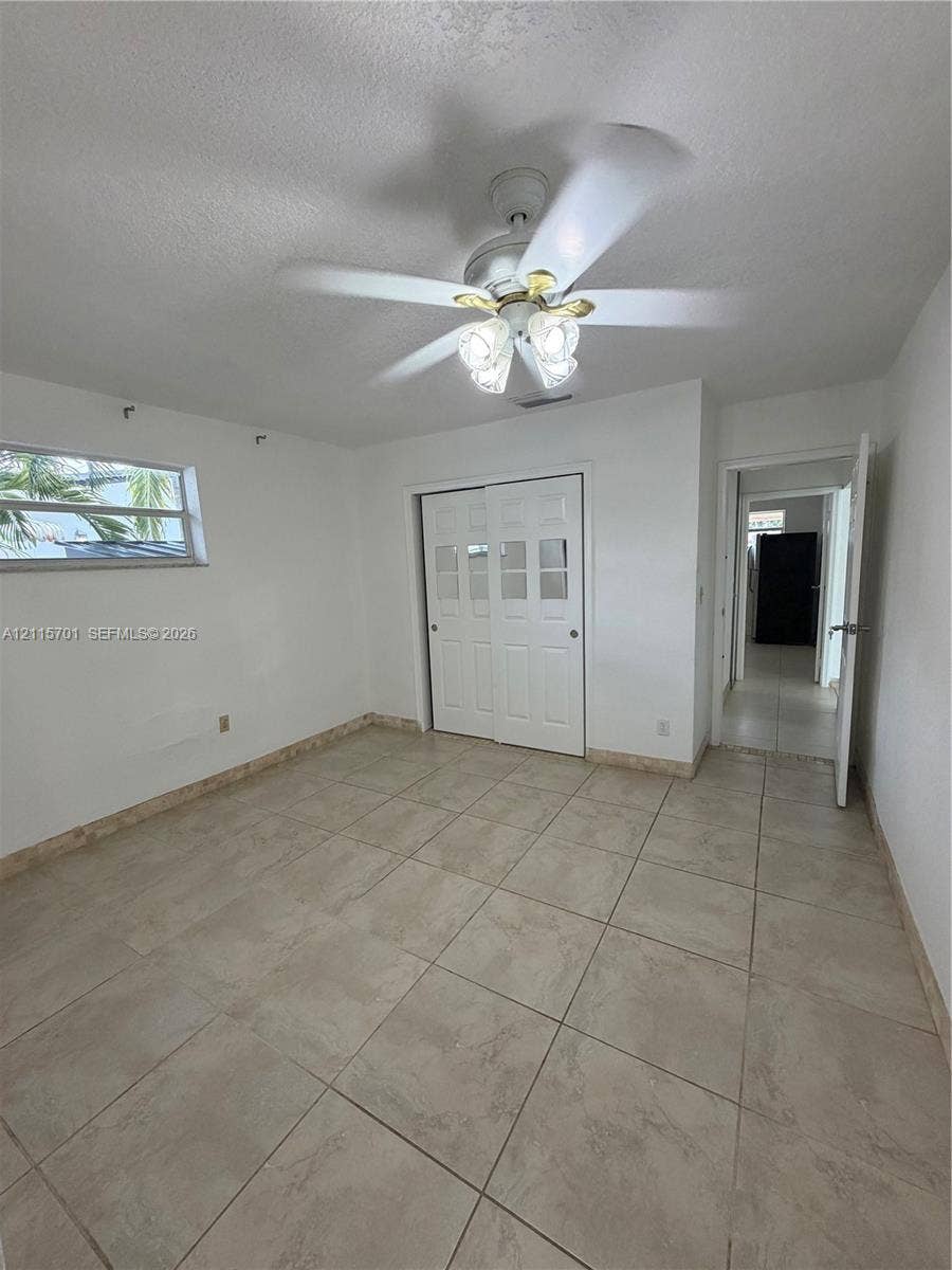 8641 NW 25th Court, #864, Sunrise, Sunrise, FL 33322 Room featuring large-format ceramic tile flooring, a multi-pane sliding closet door, and a ceiling fan with integrated lighting