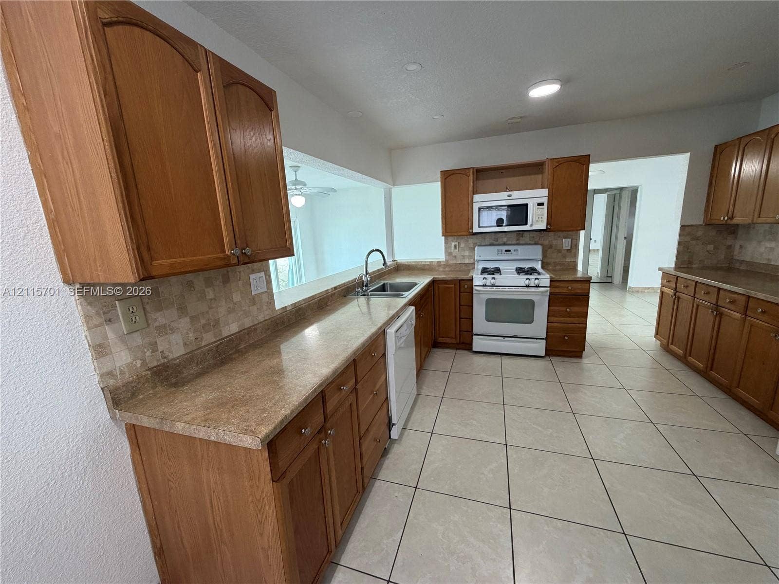 8641 NW 25th Court, #864, Sunrise, Sunrise, FL 33322 Kitchen featuring natural wood cabinetry, stone-finish countertops, tiled backsplash, integrated appliance suite, and ceramic tile flooring
