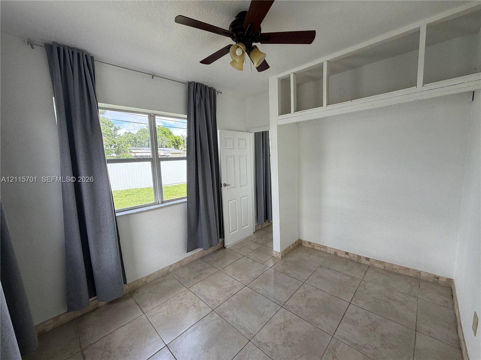 8641 NW 25th Court, #864, Sunrise, Sunrise, FL 33322 Room featuring neutral tile flooring, built-in overhead storage cabinetry, a multi-pane window, and a ceiling-mounted light fixture with a fan