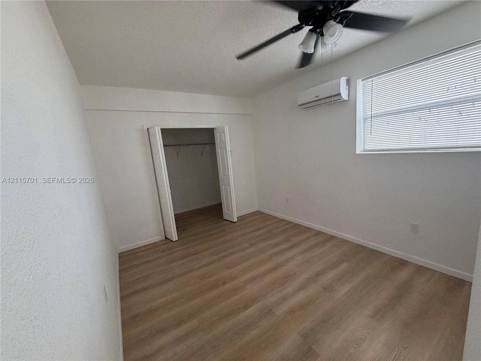 8641 NW 25th Court, #864, Sunrise, Sunrise, FL 33322 Interior room featuring wood-finish flooring, a wall-mounted ductless air conditioning unit, a ceiling fan with integrated lighting, and a closet with double-panel doors