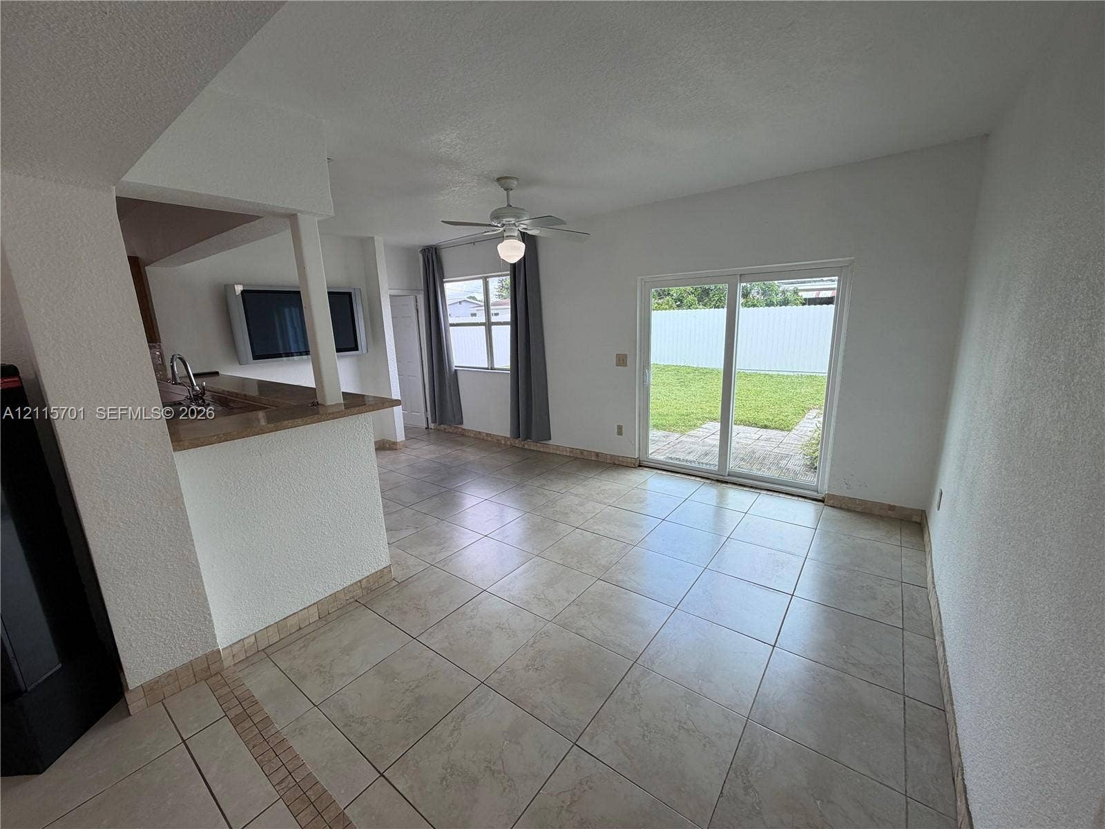 8641 NW 25th Court, #864, Sunrise, Sunrise, FL 33322 Tile flooring, kitchen breakfast bar with countertop, ceiling fan with light fixture, and sliding glass doors opening to a concrete patio and lawn
