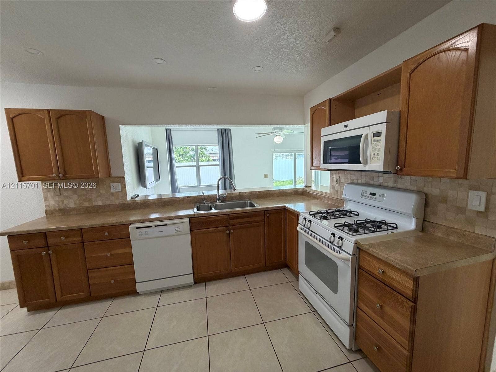 8641 NW 25th Court, #864, Sunrise, Sunrise, FL 33322 Kitchen featuring shaker-style wood cabinetry, stone-surface countertops, tile backsplash, dual-basin stainless steel sink, and recessed lighting