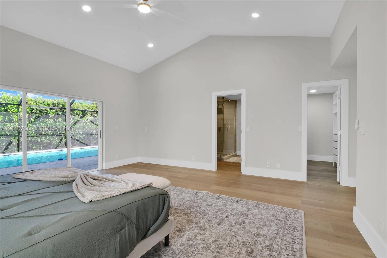 5184 Deerhurst Crescent Circle, Boca Raton, FL 33486 Vaulted ceilings, wood-finish flooring, recessed lighting, and sliding glass doors with access to a screened-in pool enclosure